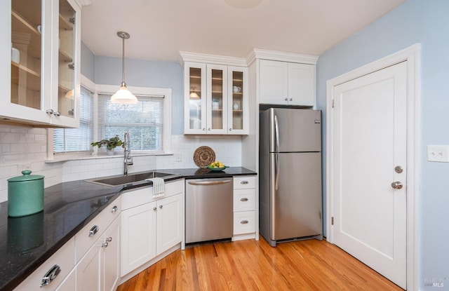 kitchen with a sink, white cabinetry, appliances with stainless steel finishes, backsplash, and light wood finished floors