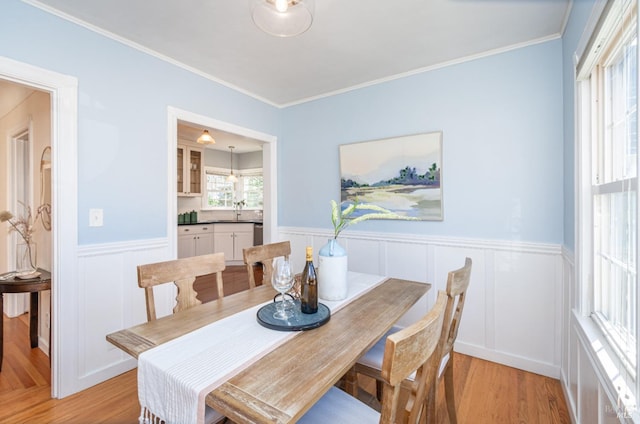 dining area featuring wainscoting, crown molding, and light wood finished floors