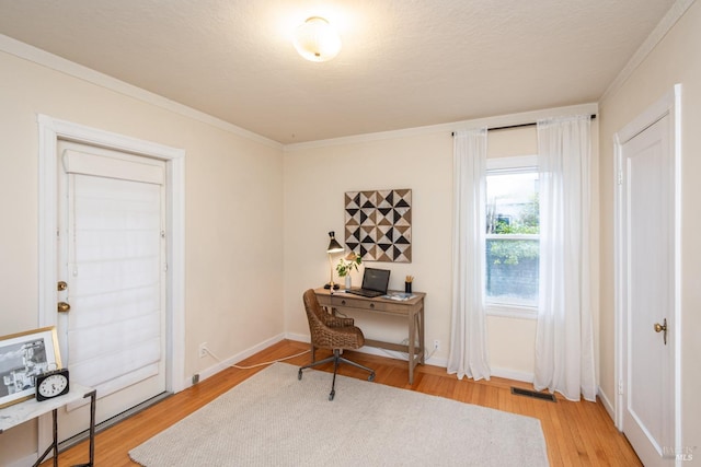 office area featuring light wood finished floors, visible vents, baseboards, and crown molding