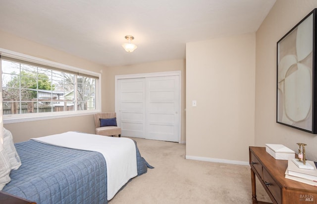 bedroom featuring baseboards, a closet, and light colored carpet