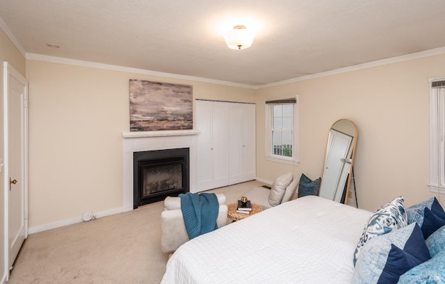 bedroom featuring carpet floors, baseboards, crown molding, and a glass covered fireplace