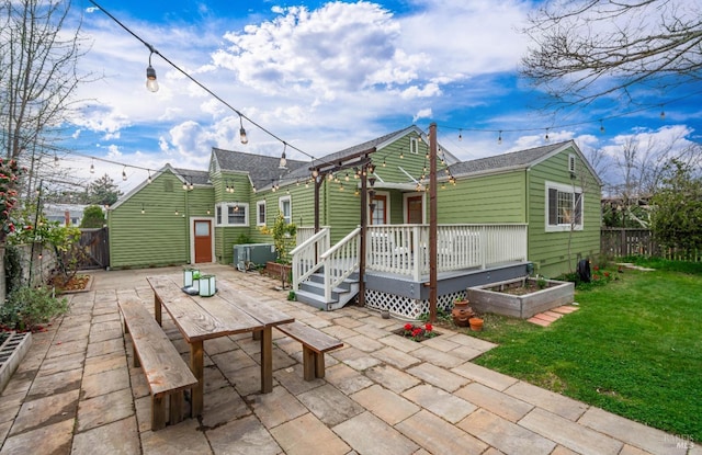 rear view of house featuring a deck, a yard, a patio area, and a fenced backyard