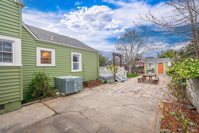 view of patio featuring cooling unit, fence, and an outbuilding