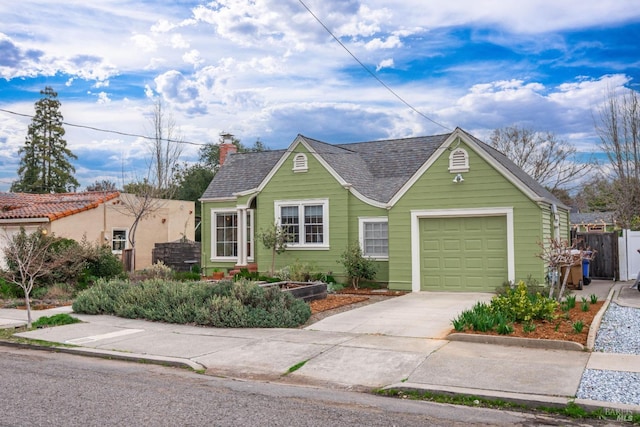 view of front facade with a chimney, a shingled roof, concrete driveway, fence, and a garage