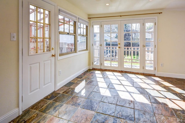 entryway with baseboards, a healthy amount of sunlight, and stone tile floors