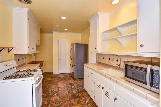 kitchen with tile counters, decorative backsplash, appliances with stainless steel finishes, white cabinetry, and a sink