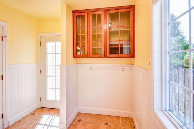 doorway featuring a wainscoted wall and light tile patterned floors