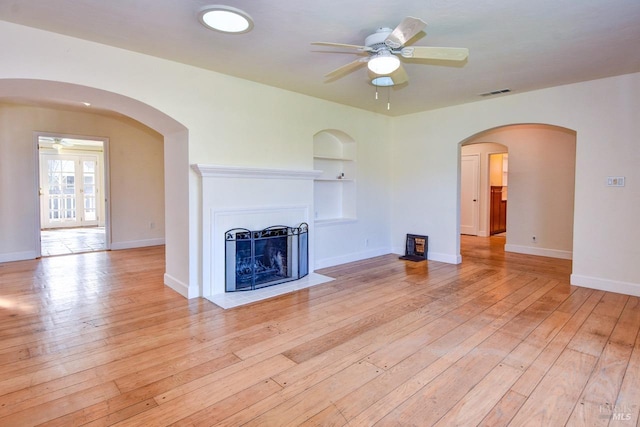 unfurnished living room with light wood finished floors, a fireplace with flush hearth, visible vents, and built in features