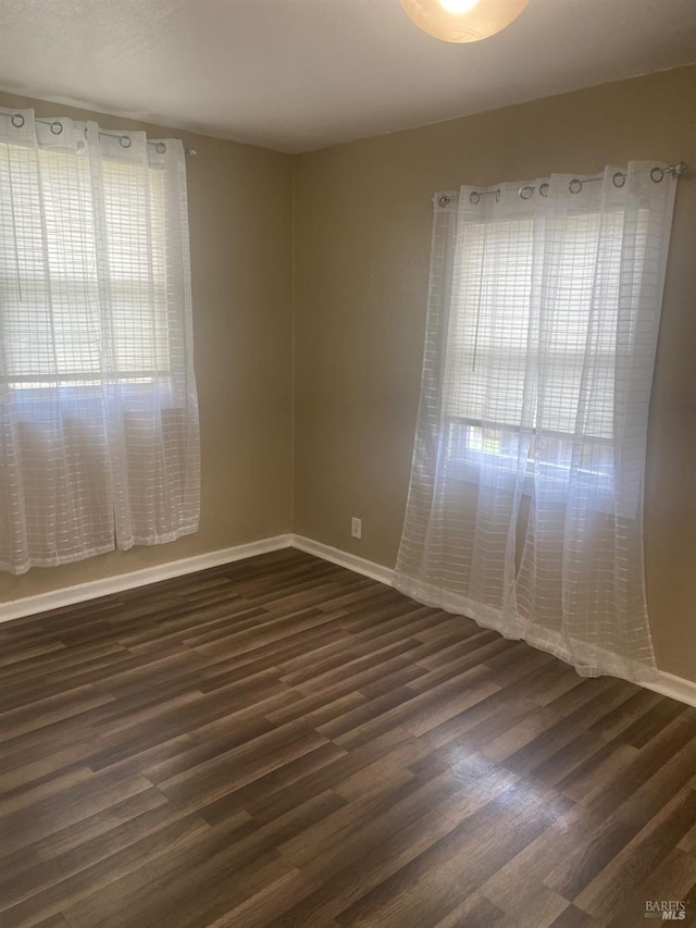 empty room featuring dark wood finished floors and baseboards