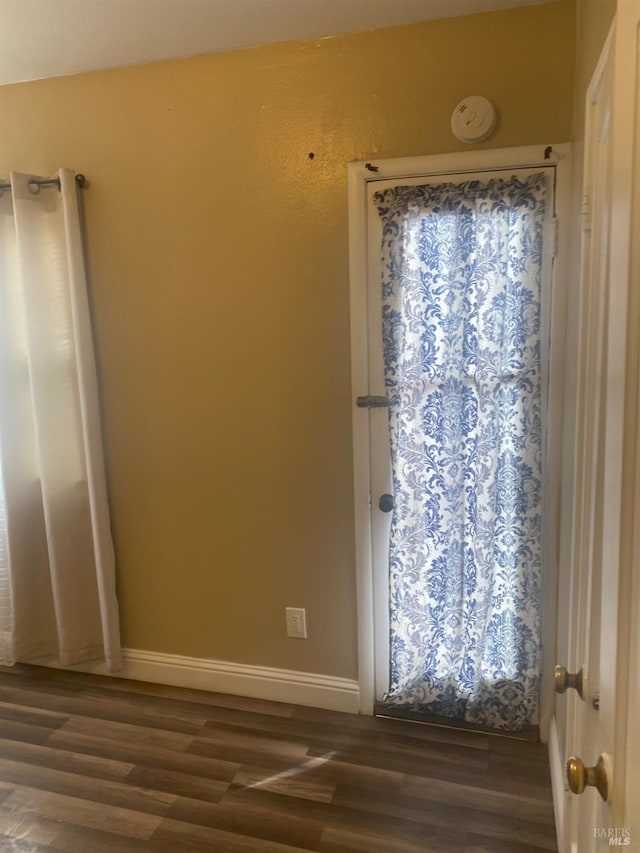 spare room featuring baseboards and dark wood-style flooring