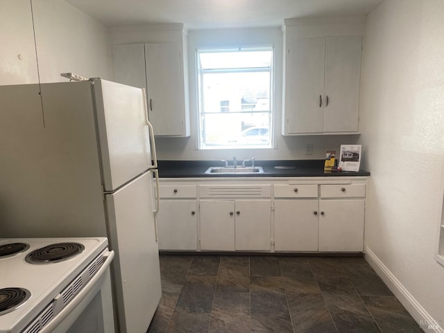 kitchen featuring dark countertops, a sink, and white cabinetry