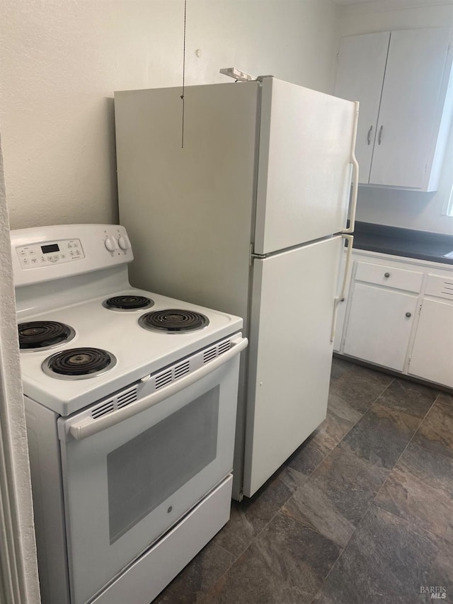 kitchen featuring stone finish flooring, white electric range oven, and white cabinetry