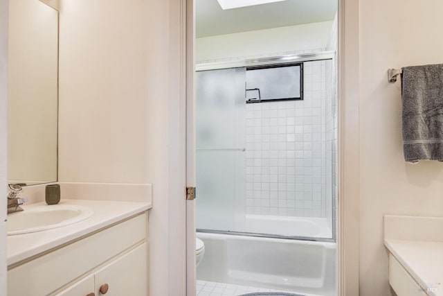 full bathroom featuring toilet, combined bath / shower with glass door, and vanity