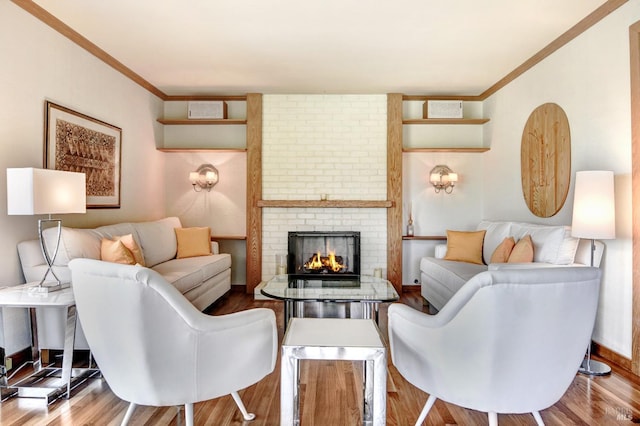 living area with ornamental molding, a fireplace, baseboards, and wood finished floors