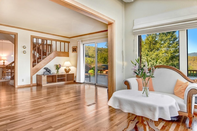 living area with wood finished floors, visible vents, crown molding, and stairs