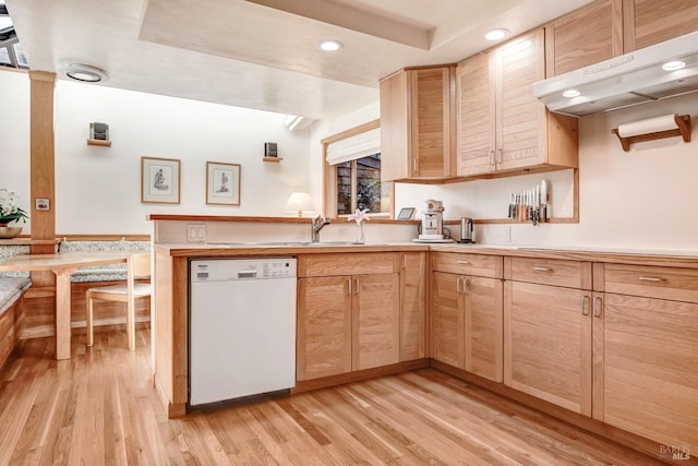 kitchen featuring light brown cabinets, light wood-style flooring, under cabinet range hood, light countertops, and dishwasher