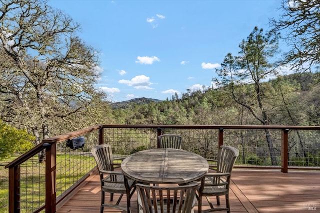 deck featuring outdoor dining space and a forest view