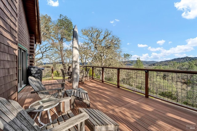 wooden deck with a mountain view and outdoor dining area