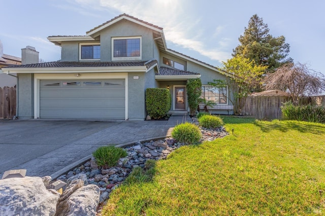 traditional-style home featuring driveway, a front lawn, fence, and stucco siding