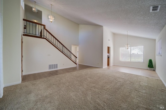 unfurnished living room featuring stairway, visible vents, a chandelier, and light colored carpet