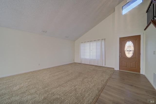 foyer entrance with high vaulted ceiling, visible vents, a textured ceiling, and baseboards