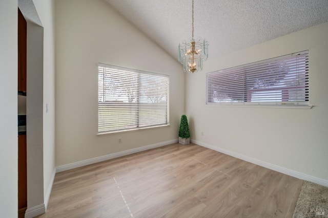 unfurnished room featuring lofted ceiling, a textured ceiling, a chandelier, light wood-type flooring, and baseboards