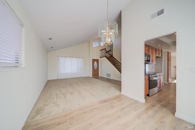 unfurnished living room featuring light wood finished floors, visible vents, an inviting chandelier, plenty of natural light, and stairs