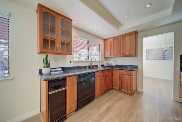 kitchen featuring a tray ceiling, brown cabinets, glass insert cabinets, a sink, and dishwasher