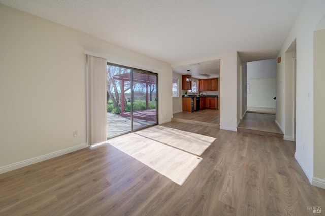 unfurnished living room featuring light wood-type flooring and baseboards