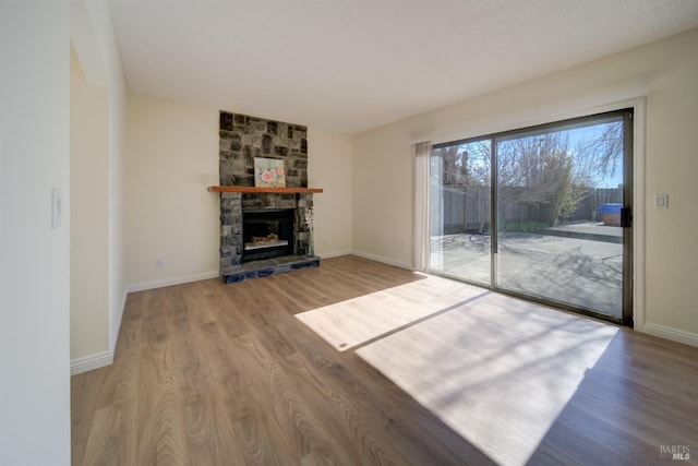 unfurnished living room featuring baseboards, a fireplace, and light wood finished floors