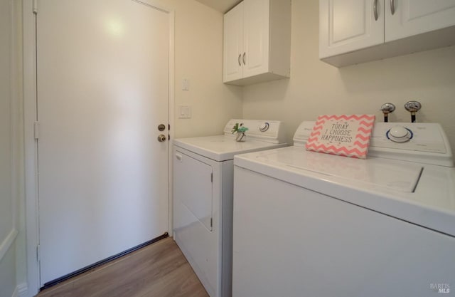 washroom featuring washer and clothes dryer, light wood-type flooring, and cabinet space