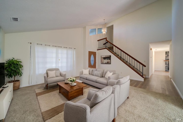 living room with high vaulted ceiling, visible vents, stairway, and baseboards