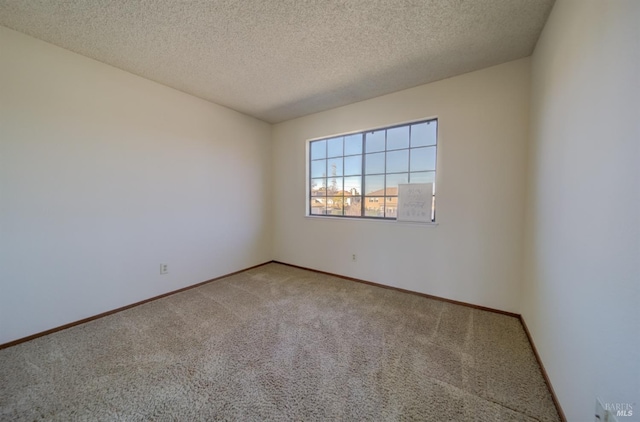 empty room featuring a textured ceiling, carpet floors, and baseboards