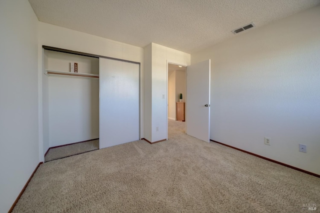 unfurnished bedroom with carpet floors, a closet, visible vents, and a textured ceiling