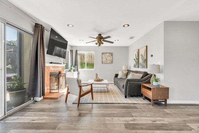 interior space featuring light wood-style flooring, recessed lighting, a ceiling fan, baseboards, and a glass covered fireplace