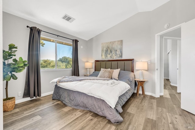 bedroom with vaulted ceiling, baseboards, visible vents, and light wood-style floors