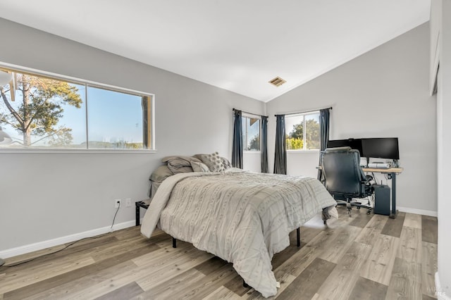 bedroom featuring lofted ceiling, light wood-type flooring, visible vents, and baseboards