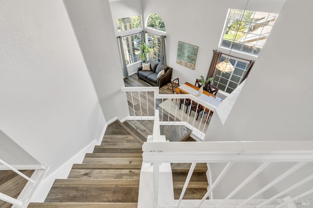 stairs with a towering ceiling, baseboards, and wood finished floors