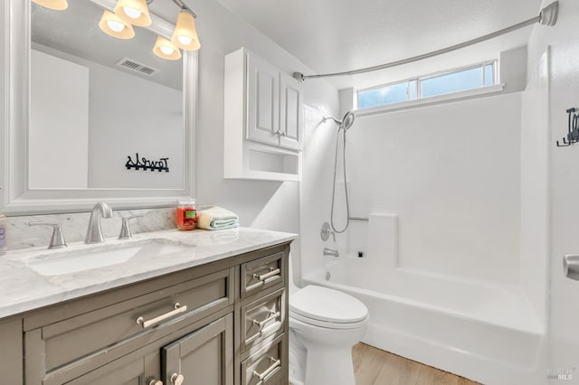 bathroom with visible vents, toilet, vanity, shower / tub combination, and wood finished floors