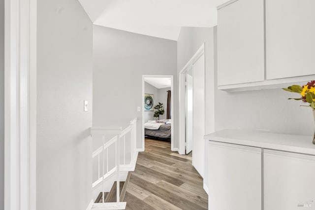 hallway with light wood-type flooring and an upstairs landing