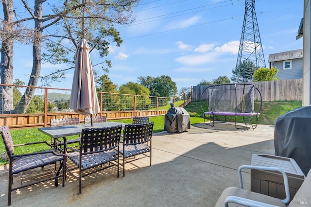 view of patio / terrace with outdoor dining area, a trampoline, a fenced backyard, and a grill