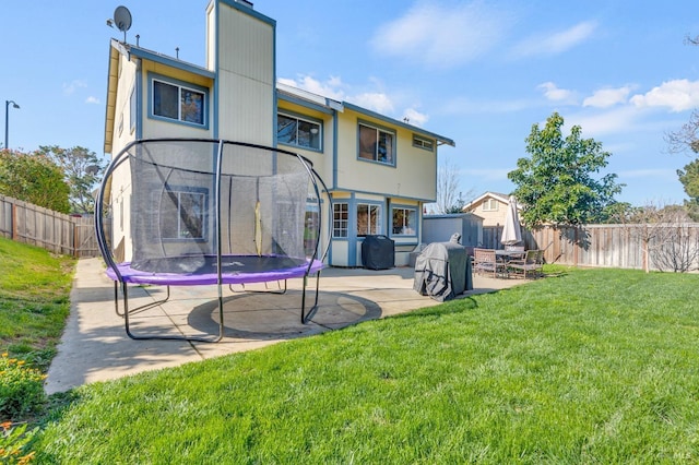 back of property featuring a patio, a trampoline, a fenced backyard, and a lawn