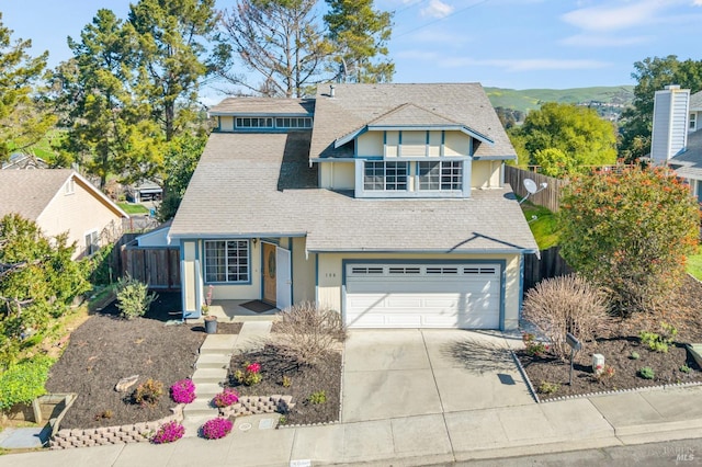 traditional-style home featuring driveway, a shingled roof, an attached garage, fence, and stucco siding