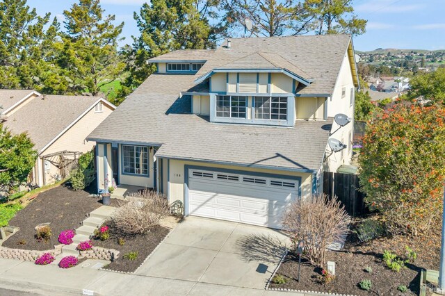 tudor-style house with a shingled roof, concrete driveway, fence, and stucco siding