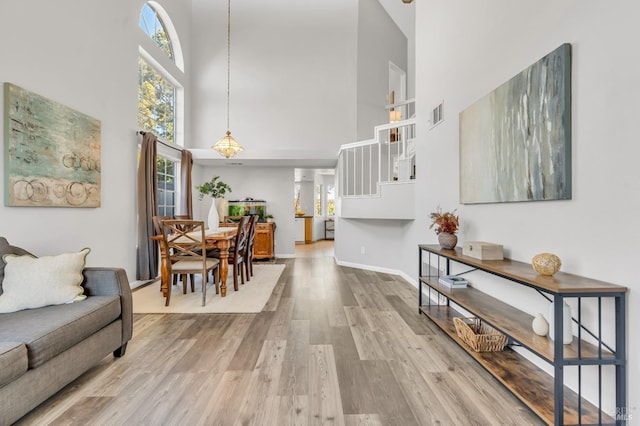 interior space featuring baseboards, visible vents, a towering ceiling, wood finished floors, and stairs