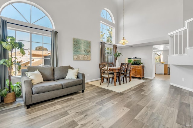 living room featuring light wood-style flooring, a high ceiling, and baseboards