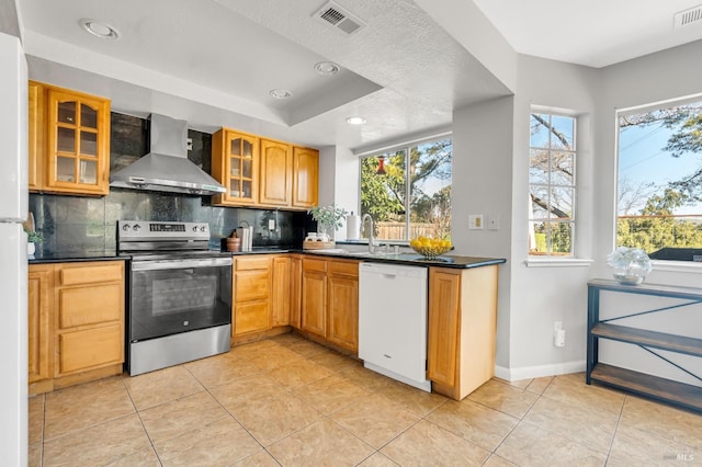 kitchen with wall chimney range hood, stainless steel electric range, dishwasher, dark countertops, and glass insert cabinets