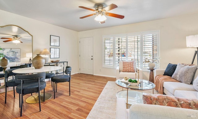 living room with baseboards, a ceiling fan, and light wood-style floors