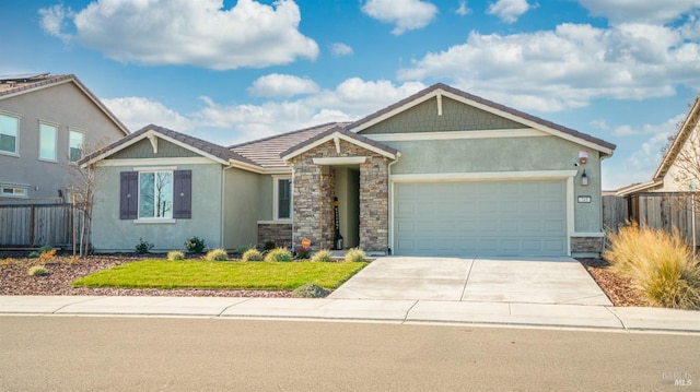 view of front of house featuring stucco siding, an attached garage, fence, stone siding, and driveway