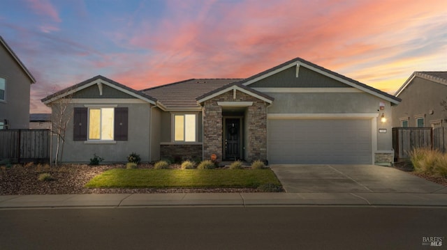 view of front of house with concrete driveway, stone siding, an attached garage, a yard, and stucco siding